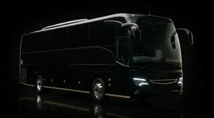 Un'inquadratura monumentale e low-key di tre quarti anteriore di un moderno Bus Gran Turismo nero lucido totalmente neutro senza marchi, illuminato da luci di profilo su sfondo nero assoluto