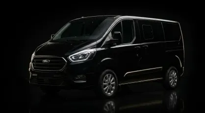 Un'inquadratura professionale e low-key di tre quarti anteriore di un Ford Tourneo Custom Van nero lucido, illuminato da luci di profilo su sfondo nero assoluto, per la sezione flotta.